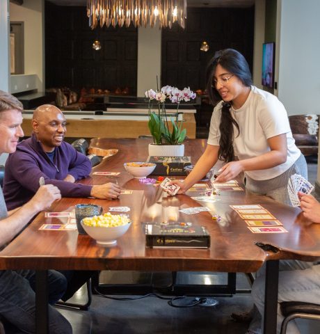 Candid photo of group of friends playing card game at table